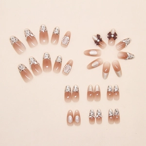 Detailed set of almond press-on nails with nude gradients, 3D bows, and pearl accents