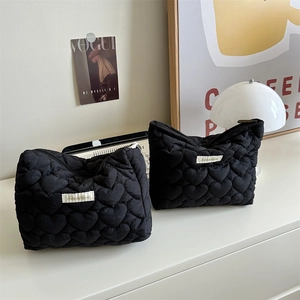 Detailed view of black quilted heart-patterned cosmetic bags for makeup storage.