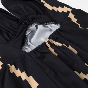 Dettaglio dell'abito con scollo all'americana con motivi geometrici beige e drappeggio