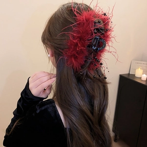 Detail of elegant red ostrich feather and black bead hair claw on model hairstyle