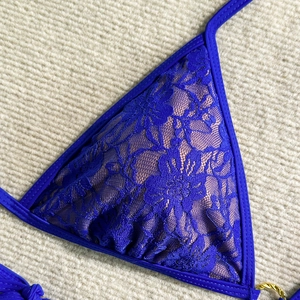 Macro shot of royal blue lace bikini top with floral eyelets and gold ring detail