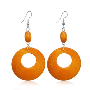 Détail de boucles d'oreilles en bois orange avec design creux et crochets argentés