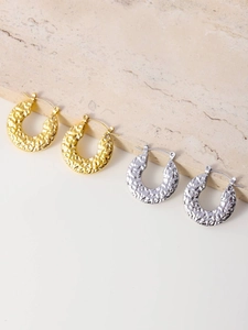 Detail of gold and silver hammered texture hoop earrings on marble stone display