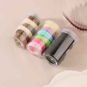 Three jars of colorful jacquard hair ties in assorted earthy and candy color tones