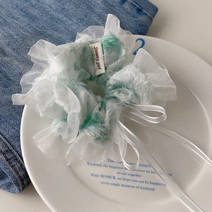 Detail of floral scrunchie with lace edges and Sweety Girl ribbon on white plate