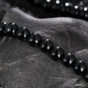 Macro shot of polished black beads on dark rock texture showing glossy surface detail