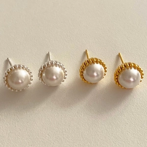Detail of vintage 925 sterling silver pearl stud earrings with textured gold and silver borders
