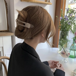 Close-up of a matte beige claw clip holding a woman's hair in a stylish updo style