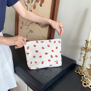 Détail du sac à bandoulière en velours côtelé blanc avec motif fraise et fermeture éclair