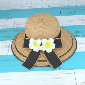 Vue détaillée du chapeau de paille avec ruban noir et fleurs de frangipanier tropicales