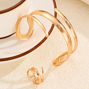 Detail of gold spiral leaf cuff bracelet and ring set on a white coffee cup