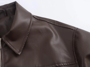 Close-up detail of dark brown leather aviator jacket showing collar seams and silver zipper