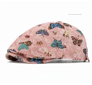 Detail einer rosa Baskenmütze mit bunten Schmetterlingsstickereien auf Webstoff