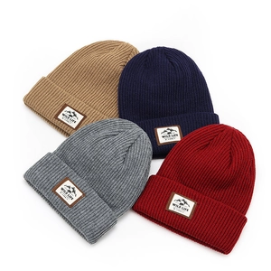 Close-up of four thick knitted beanies with vintage outdoor adventure patches