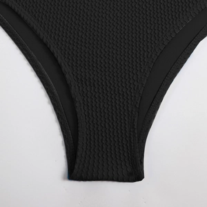 Detailed view of black honeycomb textured fabric and high-waist cut of the bikini bottom