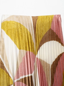 Detail of pleated fabric with abstract leaf print in yellow, pink and brown tones