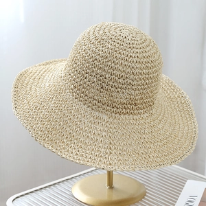 Detail of natural beige woven straw hat on gold stand with wide brim texture