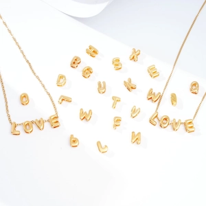 Close-up of golden bubble letter necklace pendants spelling LOVE and assorted A-Z beads