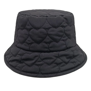 Close-up of black quilted bucket hat with heart embroidery and plush padded texture