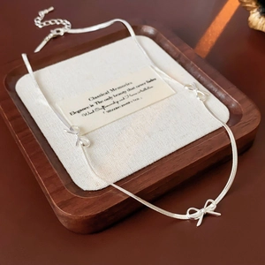 Close-up of silver bow bracelet on a vintage wooden tray with an elegant quote card