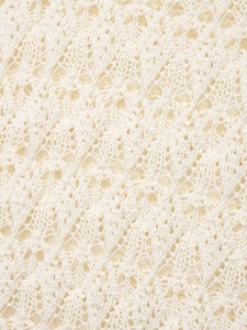 Gros plan du tissu du gilet en maille crème montrant les détails du motif ajouré