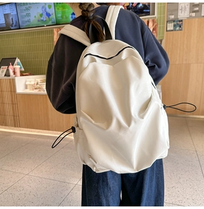 Detailed view of cream nylon backpack with pleated texture and black top handle design