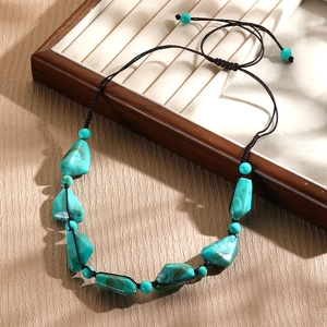 Detail of turquoise beaded necklace with adjustable brown cord on a wooden stand