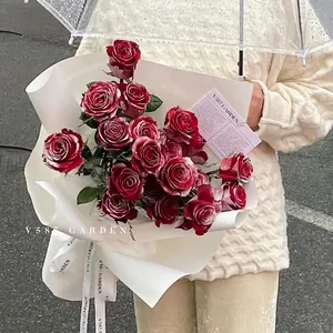Artificial snow spray on red rose bouquet with white wrapping held by a model