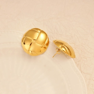 Detail shot of golden circular stud earrings with woven texture on a white plate