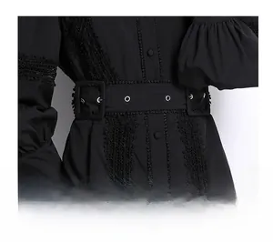 Close-up of black dress featuring lace stitching details and wide belt with metal eyelets