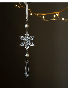 Detail of transparent acrylic snowflake pendant with pearls and warm holiday lights