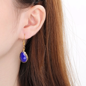 Gros plan d'une boucle d'oreille goutte d'eau dorée avec pierre bleu foncé sur mannequin