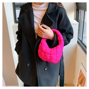 Close-up of pink quilted cloud bag worn by a model in a modern minimalist indoor setting