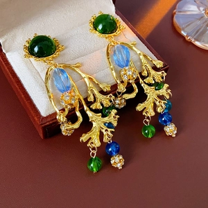 Detailaufnahme von Vintage-Goldohrringen mit grünen Steinen in einer braunen Schmuckschatulle