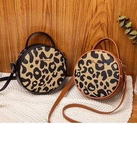Detail of round leopard print crossbody bags with metal logo and adjustable shoulder straps