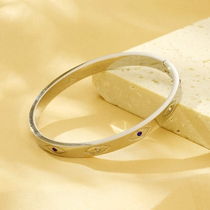 Detailed close-up of a silver devil eye bangle with blue and clear zircon inlay settings