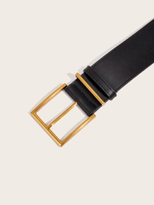 Dettaglio di una cintura vintage in pelle nera con fibbia quadrata in metallo dorato lucido