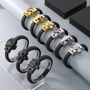 Close-up of woven leather bracelets with lion, skull, and wolf heads in various metal finishes