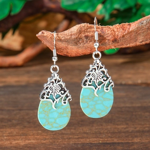Detailed view of bohemian teardrop earrings hanging on a rustic wooden branch