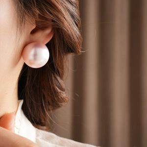 Close-up of elegant pale pink round pearl earrings worn to show size and luster