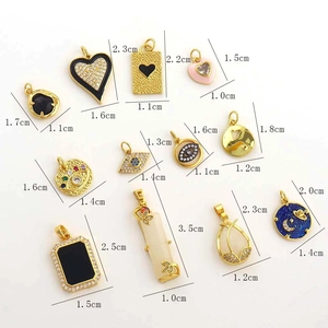 Detailed view of 18k gold heart and evil eye pendants with black enamel and zircons