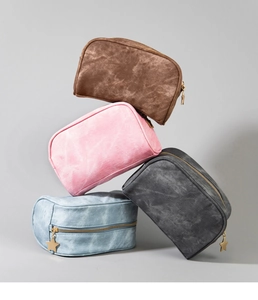 Stack of denim texture toiletry bags in four colors with gold star zippers