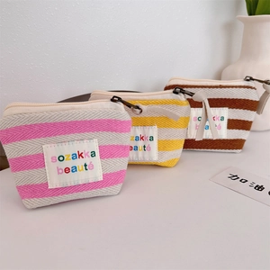 Detailed view of three striped canvas cosmetic bags with colorful sozakka logo labels