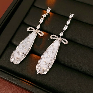 Detail of silver drop earrings with bow and cubic zirconia in a black leather box