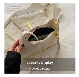 Detail view of cream leather shoulder bag interior with gold chain and zipper pocket