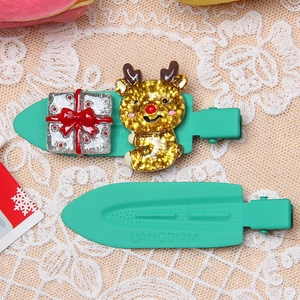 Detailed close-up of green hair clips with gold reindeer and gift box on lace background