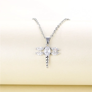 Silver titanium steel dragonfly necklace with sparkling cubic zirconia on a beige background