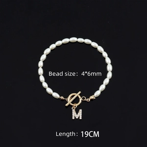 Elegant oval pearl bracelet with crystal M letter charm and gold OT clasp on black background