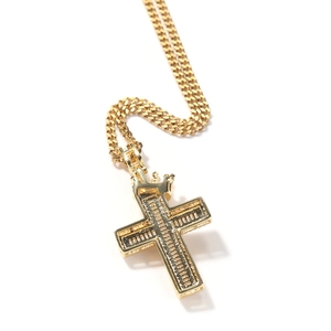 Macro shot of gold cross pendant with crown bail and polished Cuban link chain