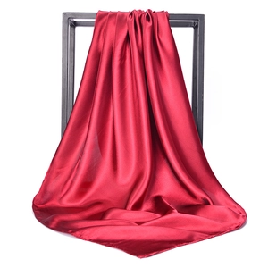 Detail of red satin silk square scarf with high gloss finish on black display frame
